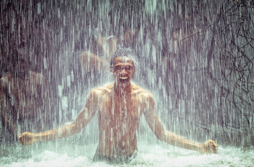 Homem feliz embaixo de uma cachoeira ou na chuva. Imagem: Pixabay